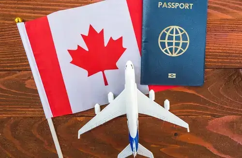 Canadian Passport on the table next to Canadian flag and a toy airplane